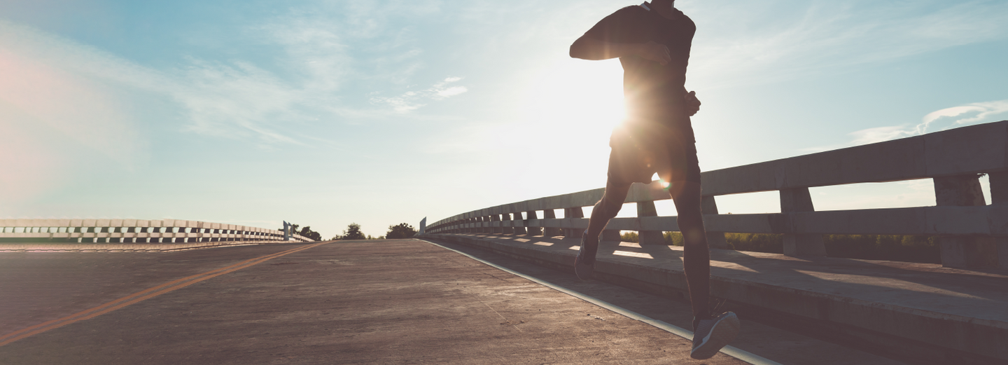 Athletic person running on bridge at sunrise