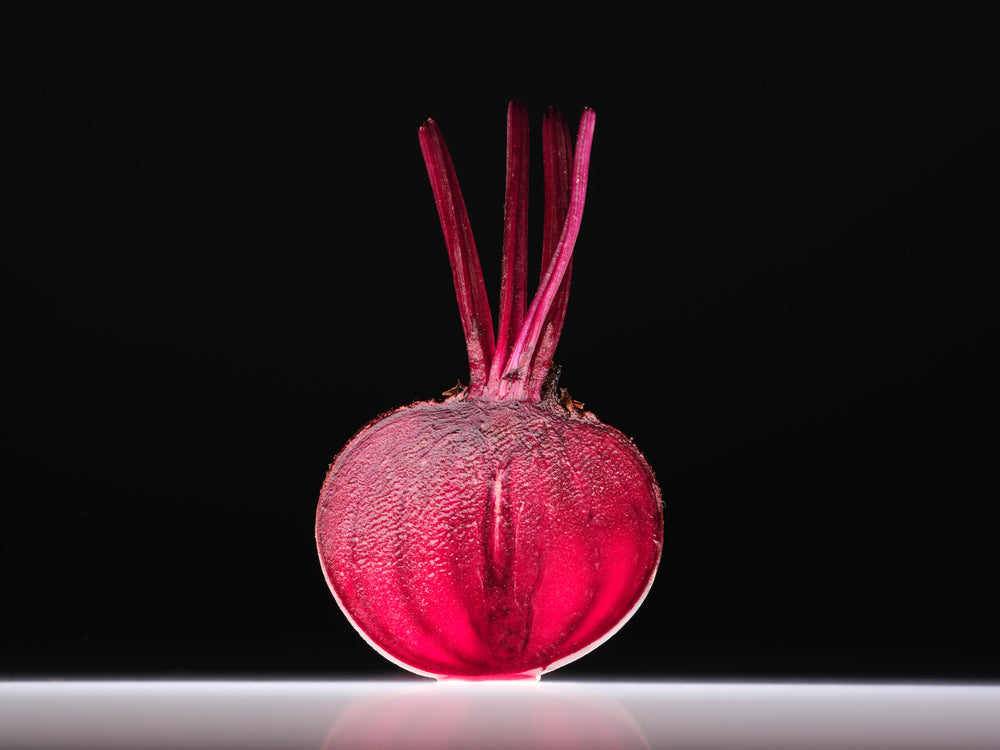 Single beetroot on a reflective surface with a black background